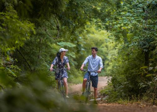 a man and a woman riding bikes down a dirt road at The Float House River Kwai in Sai Yok