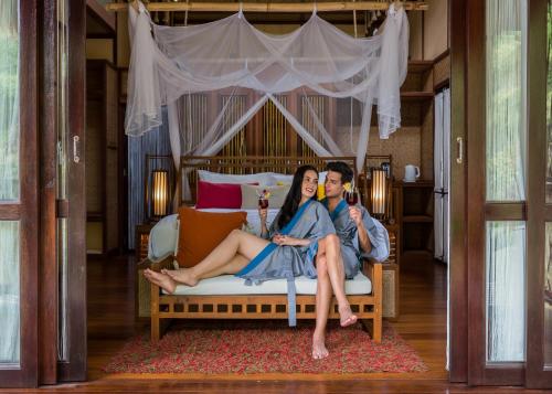 a man and a woman sitting on a bed at The Float House River Kwai in Sai Yok