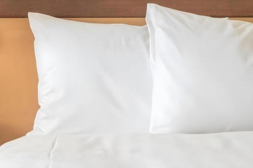 two white pillows sitting on top of a bed at RH Hotel Sibu in Sibu