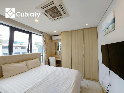 a bedroom with a white bed and a tv at Cubicity Hidden House in Ho Chi Minh City
