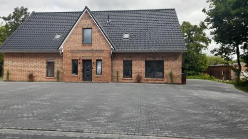 una casa di mattoni con tetto nero su un vialetto di Ferienwohnung1 Monteurwohnung Nordsee ad Aurich