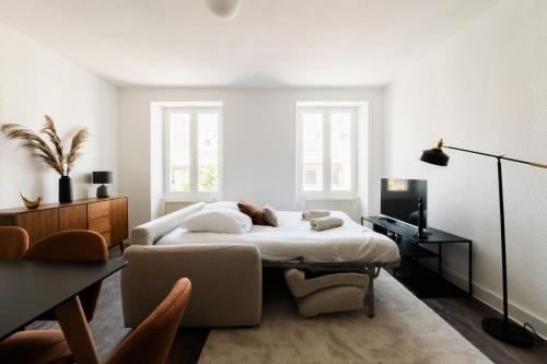 a white bedroom with a bed and a chair at Le Joubert in Valence