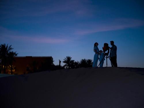 a group of people standing on top of a sand mound at Aldhafra Desert Resort, Vignette Collection by IHG in Madīnat Zāyid