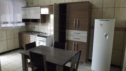 a kitchen with a table with chairs and a refrigerator at Pousada Bom Futuro in Penha