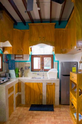 a kitchen with wooden cabinets and a sink at Casa De Moore - Ocean & Garden View Siargao in General Luna