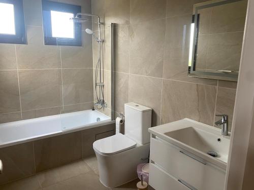 a bathroom with a toilet and a tub and a sink at Villa Pelagia Secret Valley Paphos in Kouklia
