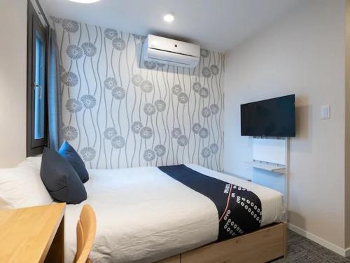 Una habitación de hotel con una cama y un televisor. en I GO Hotel, en Tokio