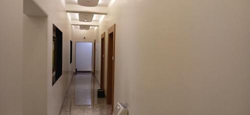 a hallway with white walls and a hallway with doors at Shine Hospitality Premium in Mumbai
