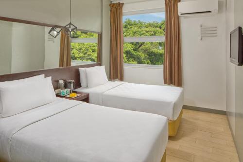 two beds in a hotel room with a window at Go Hotels Puerto Princesa in Puerto Princesa City