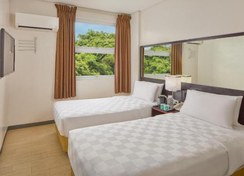 a hotel room with two beds and a window at Go Hotels Puerto Princesa in Puerto Princesa City