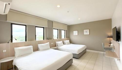 a hotel room with two beds and a tv at Country Inn in Johor Bahru
