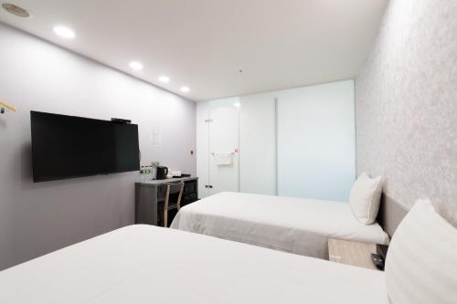 a hotel room with two beds and a flat screen tv at 歐法行旅 O Fun Hotel in Taipei