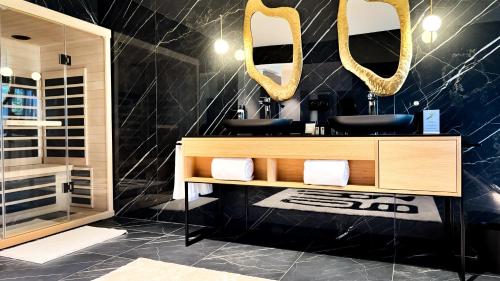 a bathroom with two sinks and mirrors on the wall at Les Lodges de Socrate in Le Vaudreuil
