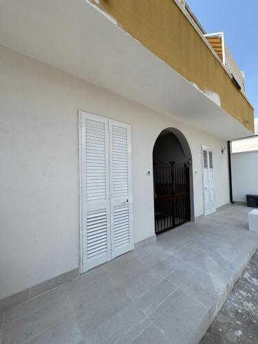 a white wall with a door and a gate at Lu Sule Lu Mare Lu Ientu in Torre Lapillo