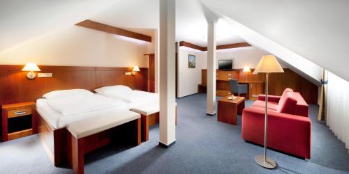 a hotel room with a bed and a red chair at Hotel Reza in Františkovy Lázně