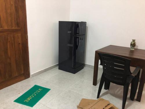 a black refrigerator in a room with a table and a chair at Crystal house in Weligama