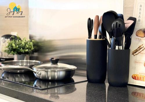 a kitchen counter with two black containers with cooking utensils at The Shore l Luxury 3BR l 6-9pax l Direct Mall Access l City Centre l Melaka River l Jonker Street by Jay Stay Management in Melaka