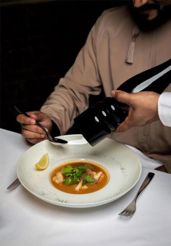 a person sitting at a table with a plate of food at Radisson Collection Muscat, Hormuz Grand in Muscat
