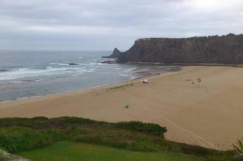 a beach with a group of people on the sand at Apartamentos Cavaco in Odeceixe