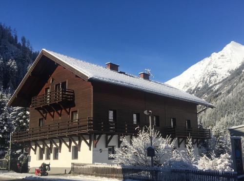 a large wooden building with snowy mountains in the background at Ski Lodge Jaktman in Bad Gastein
