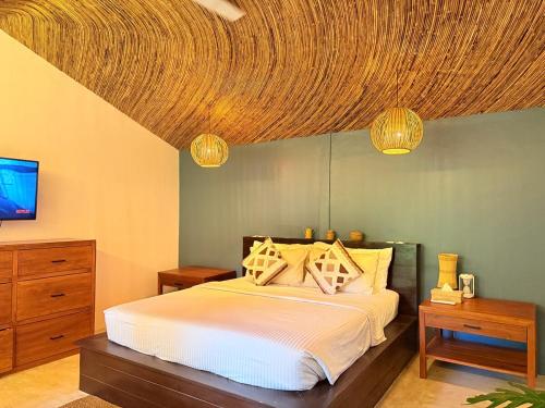 a bedroom with a bed with a wooden ceiling at Alitaptap Villa by Lugadia Villas in El Nido