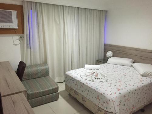a hotel room with a bed and a chair at Apartamento Boa Viagem in Recife