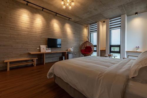 a bedroom with a bed and a desk and a television at 佇沐民宿 in Xingjian