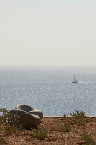 a boat on the water with a sailboat in the distance at Perma Serifos in Serifos Chora