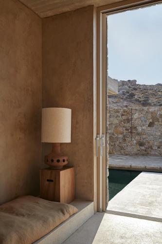a bedroom with a bed and a lamp next to a window at Perma Serifos in Serifos Chora