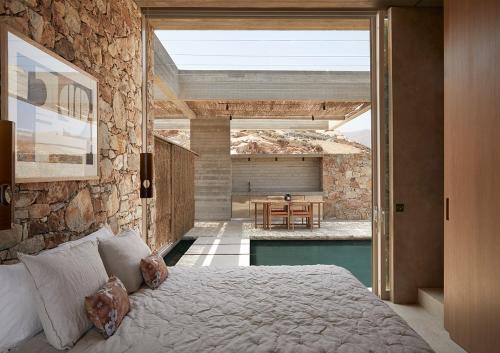 a bedroom with a bed and a patio with a table at Perma Serifos in Serifos Chora