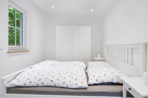 PutgartenにあるFerienhaus zum Nordstrandのベッドと窓のある白い寝室