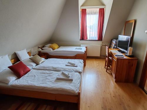 a room with two beds and a desk and a television at Il Gallo Nero - Fekete Kakas Étterem és Panzió in Szombathely