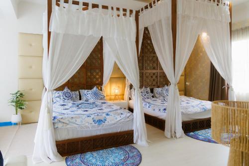 two beds in a bedroom with curtains and rugs at Sheva Om in Ban Wat Pho Thong