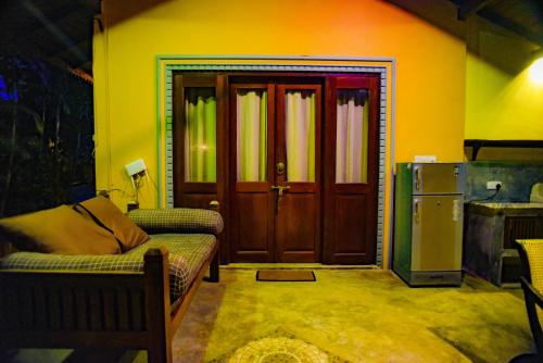 a living room with a couch and a door at Birds Cabana in Unawatuna