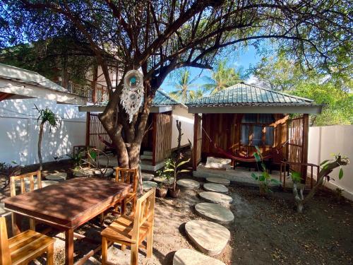 a garden with a table and a tree and a house at Gaia cottages in Gili Trawangan
