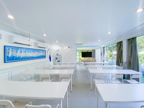 a dining room with white tables and white chairs at Sheva Om in Ban Wat Pho Thong