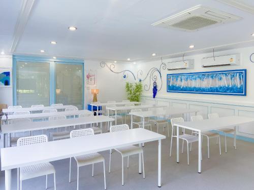 a dining room with white tables and white chairs at Sheva Om in Ban Wat Pho Thong