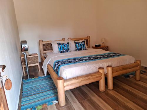a bedroom with a wooden bed with blue pillows at Kibale Canopy Lodge in Kibale