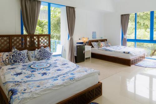 a bedroom with two beds with blue and white sheets at Sheva Om in Ban Wat Pho Thong