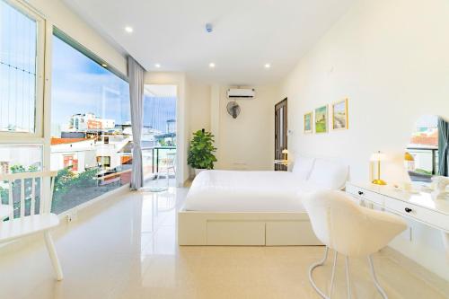 a white bedroom with a white bed and a window at Danang's house in Da Nang