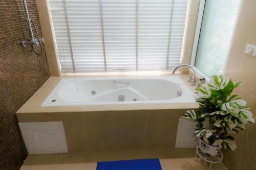 a bath tub in a bathroom with a window at Sheva Om in Ban Wat Pho Thong