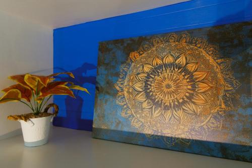 a painting sitting on a shelf next to a plant at Sheva Om in Ban Wat Pho Thong