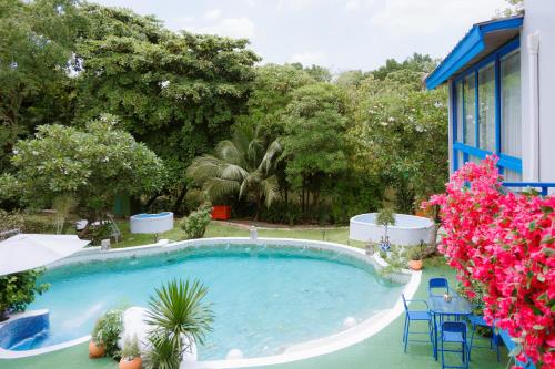 a large swimming pool in a yard with pink flowers at Sheva Om in Ban Wat Pho Thong