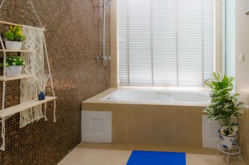 a bathroom with a tub and a window with plants at Sheva Om in Ban Wat Pho Thong