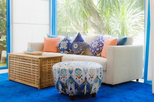 a living room with a couch and a ottoman at Sheva Om in Ban Wat Pho Thong