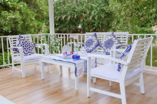 a white table and chairs with blue and white pillows at Sheva Om in Ban Wat Pho Thong