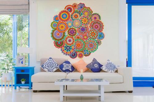 a living room with a couch with a large mandala on the wall at Sheva Om in Ban Wat Pho Thong