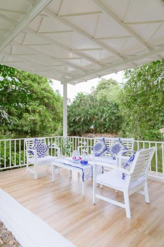 a white patio with white chairs and tables on a wooden deck at Sheva Om in Ban Wat Pho Thong