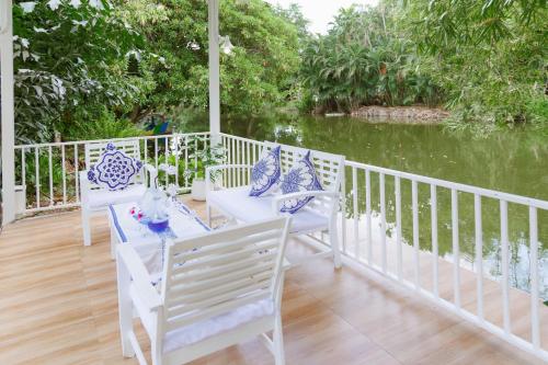 a porch with blue and white chairs and a river at Sheva Om in Ban Wat Pho Thong
