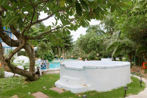 a large white tub sitting in the grass next to a tree at Sheva Om in Ban Wat Pho Thong